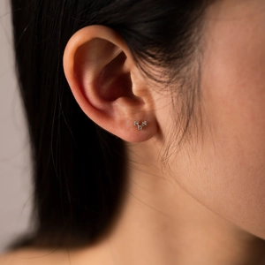 Detailed view of tiny triple zircon studs in S925 sterling silver on woman's ear