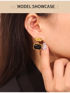 Close-up of gold-plated square studs with black glass inlays on model's ear