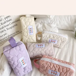 Dettaglio pochette trapuntata a fiori con toppa 'Have a nice day' e zip in primo piano