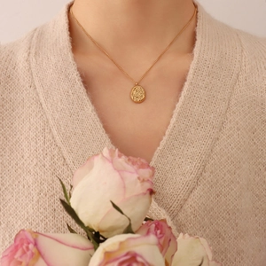Gold plated titanium necklace with irregular walnut shell textured pendant worn by a model