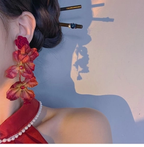 Close-up of red fabric rose flower drop earrings and hair pin on a model with shadows