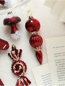Close-up of burgundy Christmas ornaments with matte and glitter finishes on white faux fur