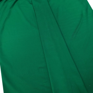 Close-up of the smooth green fabric texture with fine weave for the V-neck dress