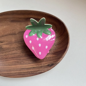 Close-up of cute pink acrylic strawberry hair claw clip with green leaf detail
