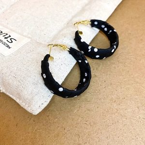 Detailed view of polka dot fabric wrapped hoop earrings on a textured background