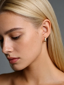 Close-up of matte brushed gold square hoop earrings worn on ear with minimalist design