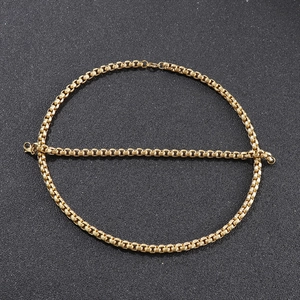 Detail of a golden box chain bracelet with robust circular links on a textured surface