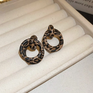Macro shot of retro leopard print double hoop earrings on a beige velvet jewelry box