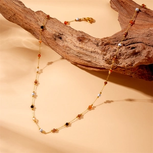 Gold plated stainless steel chain necklace with colorful natural stone beads on wood