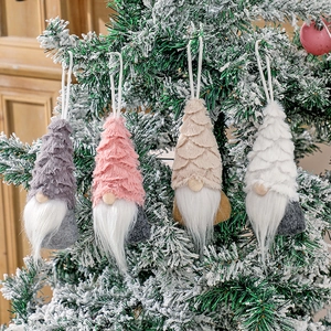 Set of four plush Christmas gnomes with long hats and beards hanging on snow-covered trees