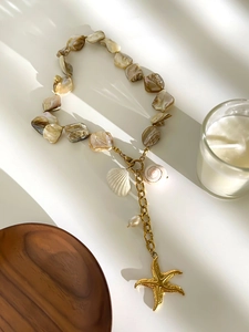 Detailed shot of starfish pendant and natural shell necklace with golden metal accents