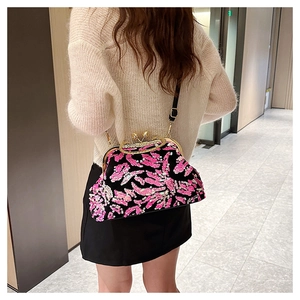 Detail of sequin shell bag featuring pink and black embroidery with metal chain strap