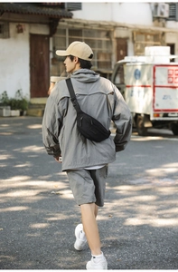 Male model wearing a black nylon crossbody bag in an urban street setting for casual daily use