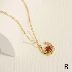 Macro detail of U-shaped gold horseshoe pendant with red gemstone and white crystals