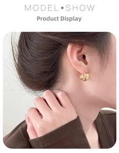 Close-up of square gold glossy acrylic earrings worn by a model for a modern commute style