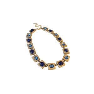Vintage gold necklace with alternating dark and light blue crystal gems in a retro style