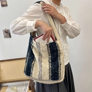 Close-up of wide striped plush tote bag with cozy sheepskin texture and shoulder strap