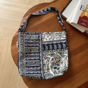 Detail of bohemian floral print canvas tote bag with long strap on a wooden table