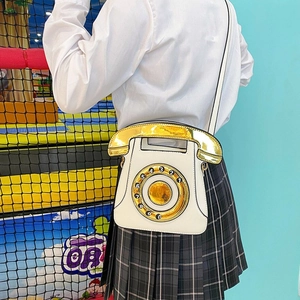 Close-up of a white vintage telephone bag featuring a rotary dial and receiver handle