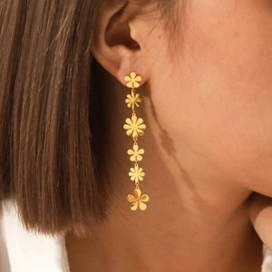 Close-up of elegant gold daisy tassel earrings worn by a model in a side profile view