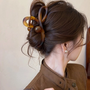Close-up of amber brown cross ball shark clip for elegant hair styling on model