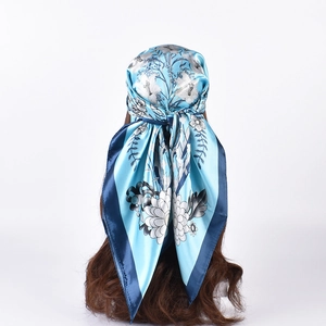 Detail view of floral satin scarf tied as a headscarf showing blue lily prints