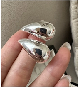 Close-up of polished silver teardrop earrings held in hand to show size and mirror finish
