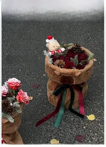 Plush bear head Christmas flower basket with red roses and pine cones on a velvet ribbon