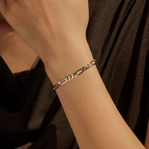 Vintage S925 sterling silver Figaro chain bracelet on female model wrist with dark backdrop
