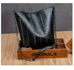 Detail of black PU leather shoulder bag featuring silver rivet studs and a metal chain strap