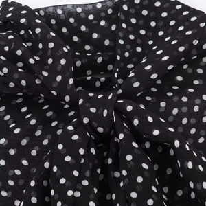 Dettaglio del tessuto in chiffon a pois bianchi e neri con elegante fiocco decorativo