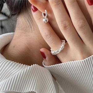 Detailed view of twisted 925 sterling silver ring and bead earrings on a model