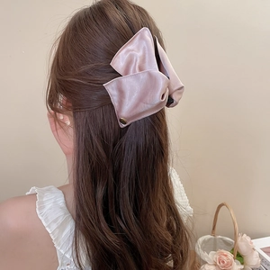 Close-up of a pink satin bow hair claw clip worn on a half-up hairstyle with elegant style