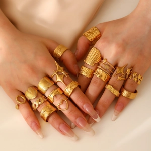 Close-up of gold-plated rings with flower, heart, and shell patterns on silk fabric