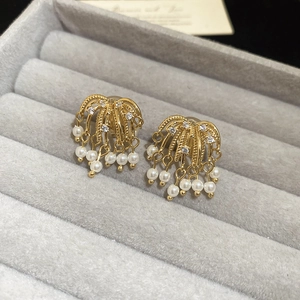 Macro detail of 18k gold plated zircon firework clip-on earrings with elegant pearl tassels