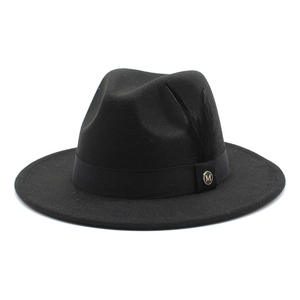 Détail du logo M en métal et décoration de plume noire sur le chapeau en feutre