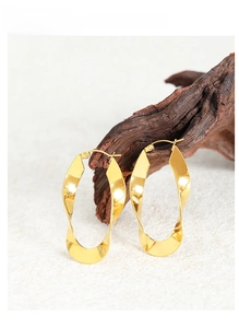 Detailed view of golden twisted U-shaped earrings on wood with mirror-polished finish