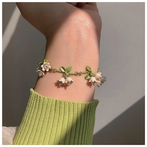 Detailed view of a lily of the valley bracelet with white flowers and green leaves