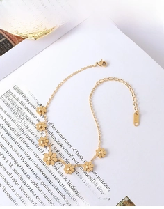 Detail of gold daisy chain anklet with lobster clasp and K18 engraving on a white background