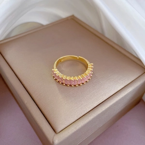 Detail of gold open ring featuring a row of pink rectangular zircon stones on silk