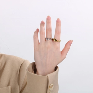 Close-up of golden and silver irregular twisted wave rings worn on a hand