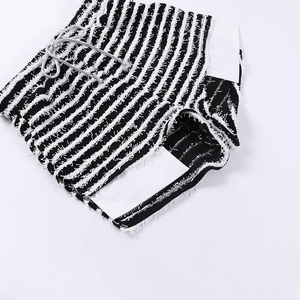 Détail du short en maille rayée avec cordon argenté et bordure à franges au bas