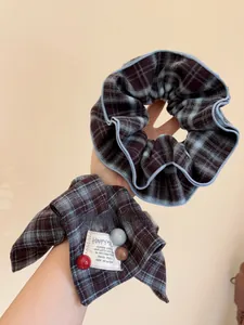 Close-up of brown plaid scrunchie and bow hair tie with decorative colored beads