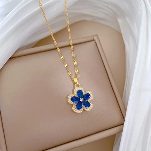Detailed macro of gold flower pendant with blue petals and sparkling crystal pavé