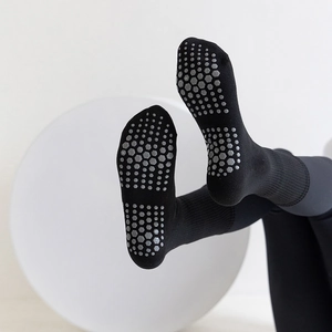 Black mid-tube yoga socks featuring non-slip grey hexagonal silicone grips on soles