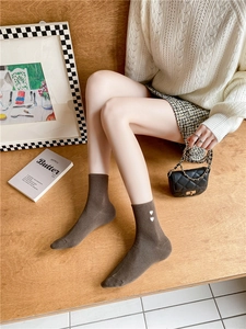 Detail of dark brown mid-calf socks with white heart embroidery in cozy autumn setting