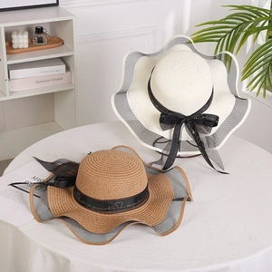 Close-up of woven straw sun hats with wavy edges and elegant love you forever ribbon detail