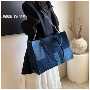 Detail of multi-tone denim patchwork tote bag with stitching and long shoulder strap