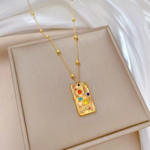 Detail of gold titanium steel necklace with rectangular pendant and colorful stones