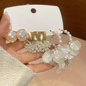 Close-up of pearl flower earrings set with rhinestones and gold finish detail